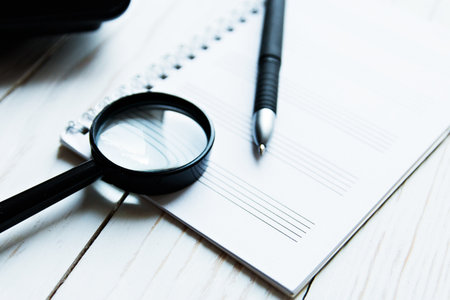 Magnifier on a laptop, notebook and pen.の写真素材