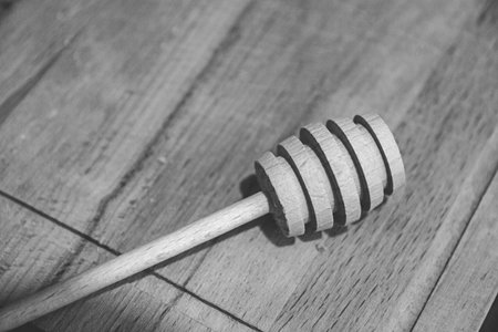 wooden wand for honey on wooden board, black and white image.の写真素材