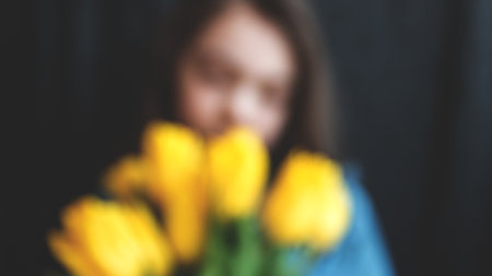 blur image of girl with a bouqet of yellow tulips on a black background.の写真素材