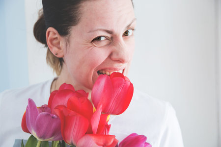 fun young girl with a bouquet of red tulips on white background.の写真素材