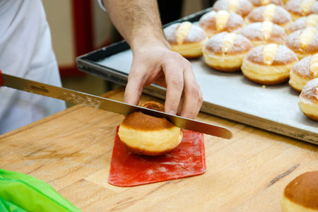 pastry chef cuts a bun with a knife to fill it with cream.の写真素材