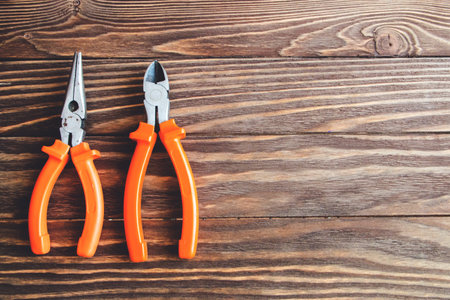 pliers and side cutters on wooden background.
