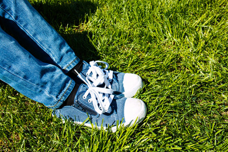 children's feet in sneakers and jeans on the green grass.の写真素材