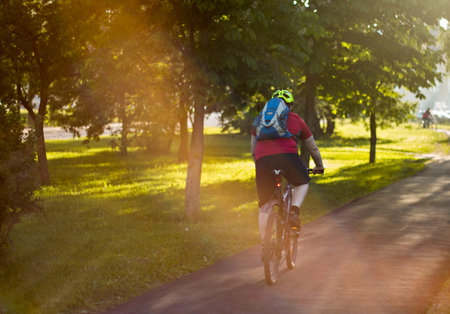cyclist in a helmet with a backpack on his back in the sun.