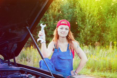Wait for roadside assistance. Portrait of a young woman standing next to her car and open car hood.の写真素材