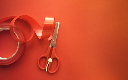 red ribbon and scissors on red background with copy space.の写真素材