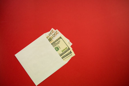 white envelope with dollars and euros on red background.の写真素材