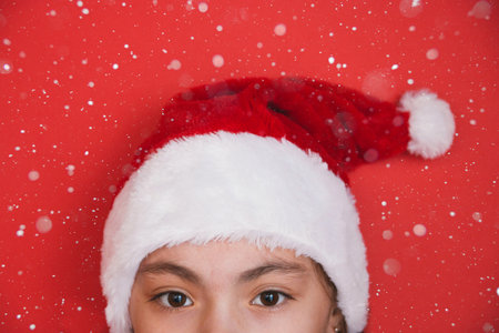 Cute little girl in Santa Claus hat on red background.の写真素材