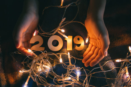 children's hands on a blanket with a shiny garland and numbers 2019, on the eve of the new year.