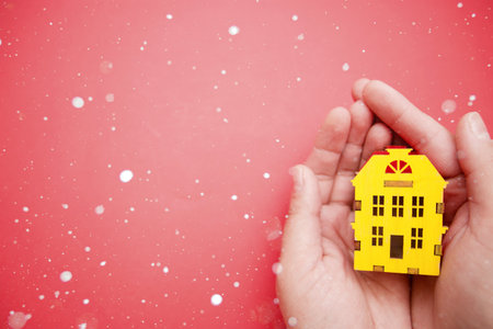 Yellow house model in female hands on red background.の写真素材