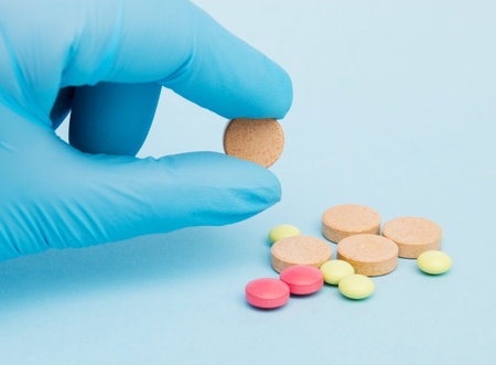 Female hand holding a tablet of medicine a choice of several drugs on the blue background.