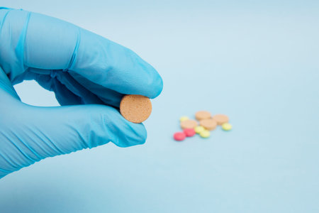 Female hand holding a tablet of medicine a choice of several drugs on the blue background.