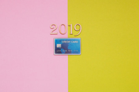 credit card and wooden numbers 2019 on pink and green background.の写真素材