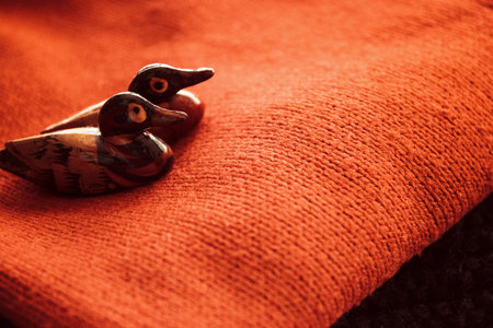 two lovebirds ducks love symbol on red wool sweater background texture, vintage image selective focus.の写真素材