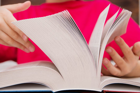 Close-up of the hand on the book is going to turn the page to the next chapter. girl leafing through the pages of the book. a girl with a book.の写真素材