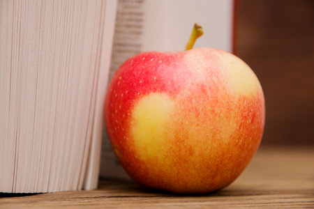 Reading book open on wooden background and red appleの写真素材