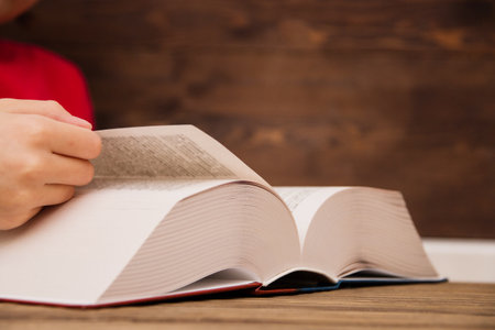 Close-up of the hand on the book is going to turn the page to the next chapter. girl leafing through the pages of the book. a girl with a book.の写真素材