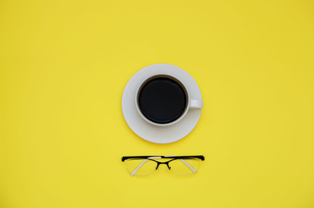 coffee Cup and glasses on yellow background with copy space.