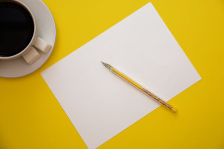 pen white paper and coffee Cup on yellow background with copy space top view.の写真素材