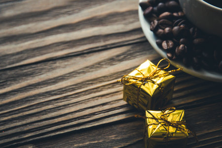 Cup of coffee, coffee beans on saucer and gifts on wooden background.の写真素材
