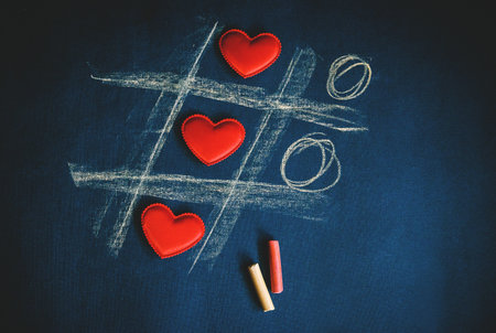 cross zero of hearts and colored crayons on dark background.の写真素材