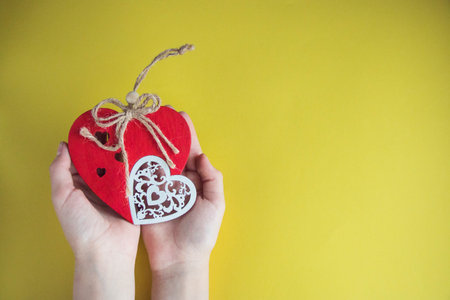 handmade red heart in hands close-up on yellow background, symbol of love, happy Valentine's day.の写真素材