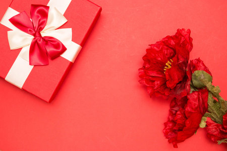 Real box with white and red bow and ribbon and red flowers top view on Valentine's day isolated on...