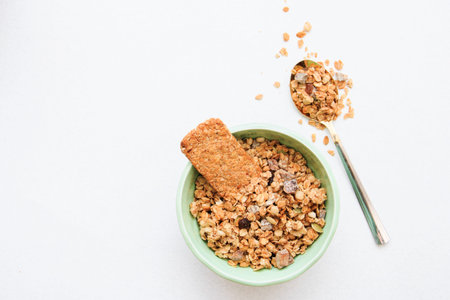 Crispy muesli in boal and on spoon dry Breakfast isolated on white background selective focus, top...