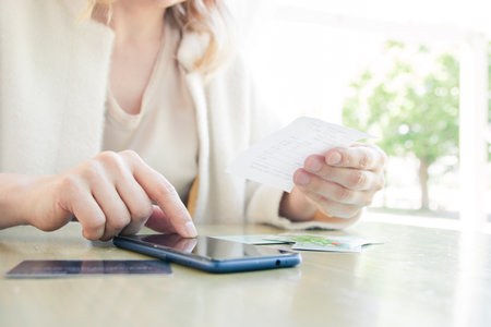 A woman in a white jacket, paying by credit card online, making orders over the Internet. Selective focus.の写真素材