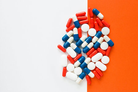 Multicolored capsules isolated two white and orange background, copyspace for text, selective focus,...