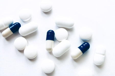 White and blue capsules isolated on white background, copyspace for text, selective focus, top view. Pain meds, health, pills for the treatment of the concept of drug abuse.の写真素材