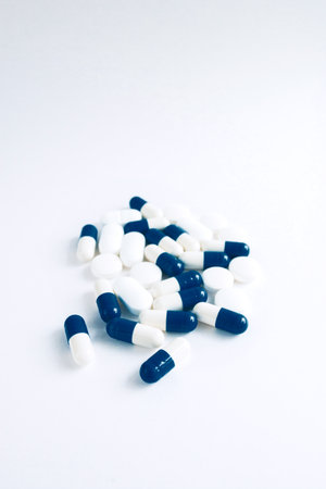White and blue capsules isolated on white background, copyspace for text, selective focus, top view. Pain meds, health, pills for the treatment of the concept of drug abuse.の写真素材