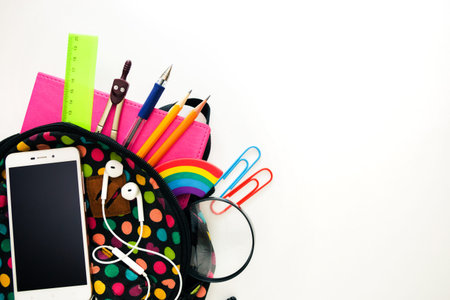 Bright colored backpack, full of school supplies, blank cell phone screen, headphones, pink...