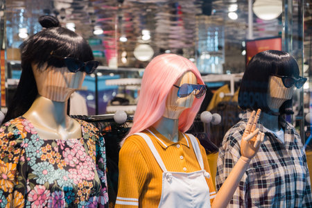 mannequins with modern clothes in fashion store display window.