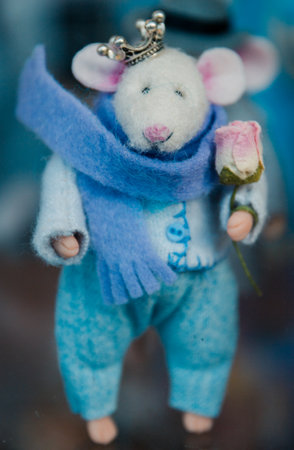 toy mouse in clothes handmade wool in the hands of a rose, a crown on his head, selective focus.の写真素材