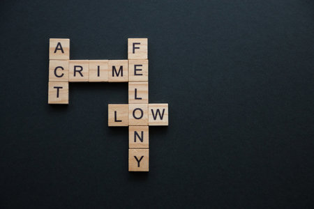 words related to crime, to the offense collected in a crossword puzzle with wooden cubes on a black background.の写真素材