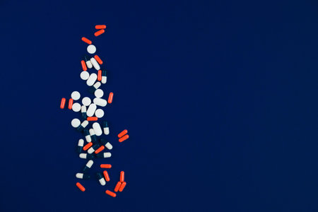 Multicolored capsules isolated on blue background, copyspace for text, selective focus, top view. Pain meds, health, pills for the treatment of the concept of drug abuse.の写真素材