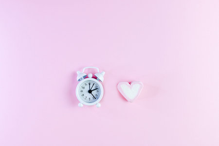 Pastel Valentine background is made of marshmallow souffle in the form of hearts on a pink background and a clock. Valentine's day concept with copy space, time to love.の写真素材