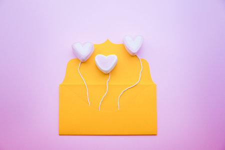 Valentine s day, pastel pink marshmallow hearts on the rope from the yellow envelope isolated on...