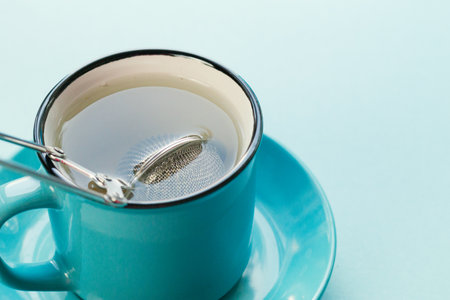 Blue background, strainer and a cup of tea.の写真素材