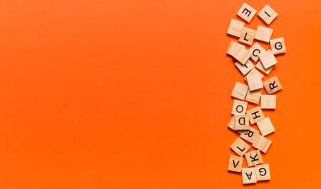 Pile of wooden letters on the surface of a orange paper background, selective focus.の写真素材