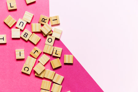 Pile of wooden letters on the surface of a pink paper background, selective focus.の写真素材