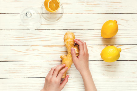 Ginger-lemon in hands on white wooden background, prevention of colds. Selective focus.の写真素材