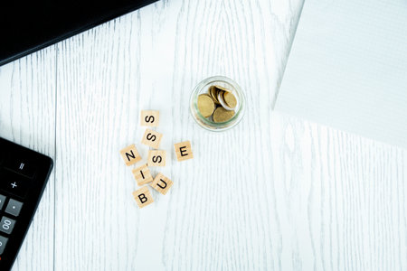 the future of Finance, business banking and financial concepts. A Flatline of a laptop, cents, a glass jar, a calculator and cubic letters on a white background. Selective focus.の写真素材
