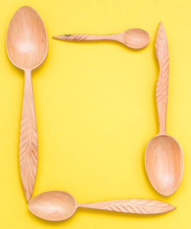 Houseware: wooden kitchen spoons, isolated on yellow background top view. Zero waste, eco friendly concept. Flat lay frame.の写真素材