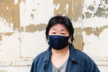 Protection of human face masks in a public place, prevention of coronavirus. Protection against the coronavirus pandemic, flu epidemic. An Asian woman aged about 65 years old in a mask poses.の写真素材