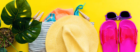 Accessories flatlay traveler on a yellow background hat, beach attributes. Concept of travel or...