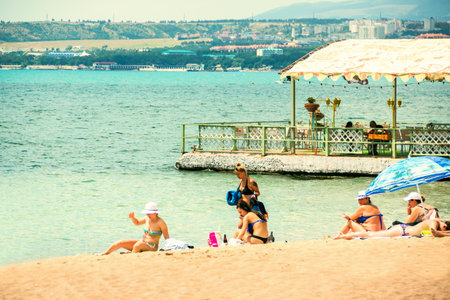 Summer, sea, vacationing people on a sandy beach, near a summer cafe. Gelendzhik, Krasnodar territory, Russia, July 2019.のeditorial素材