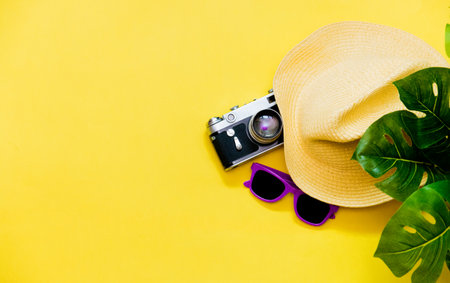 Accessories flatlay traveler on a yellow background is a hat, camera, sunglasses and a green plant. The concept of a trip or vacation with a view from above. Summer background.の写真素材