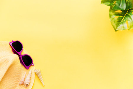 Accessories flatlay traveler on a yellow background is a hat, sunglasses and a green plant. The concept of a trip or vacation with a view from above. Summer background.の写真素材